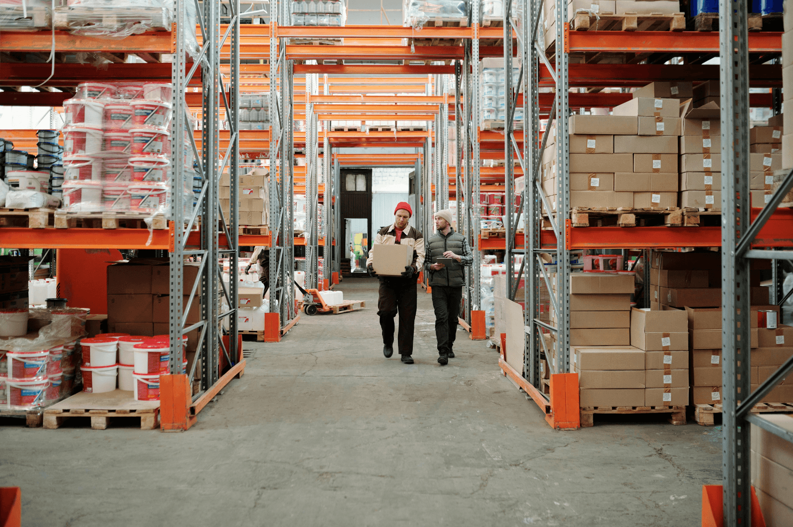 Warehouse staff walking an aisle between stocked orange racks